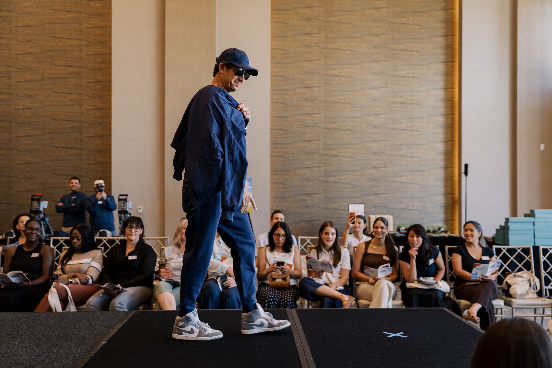 Guest walking the Fashion Forward runway in a navy tracksuit